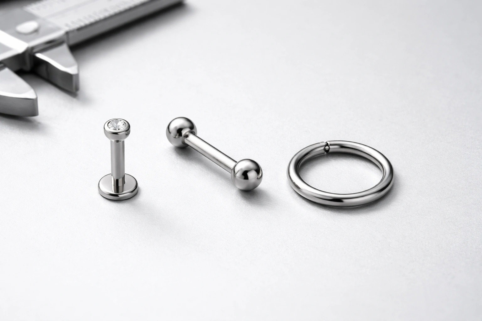 Titanium piercing jewelry precision manufacturing hero image with measuring tools and premium metal finish