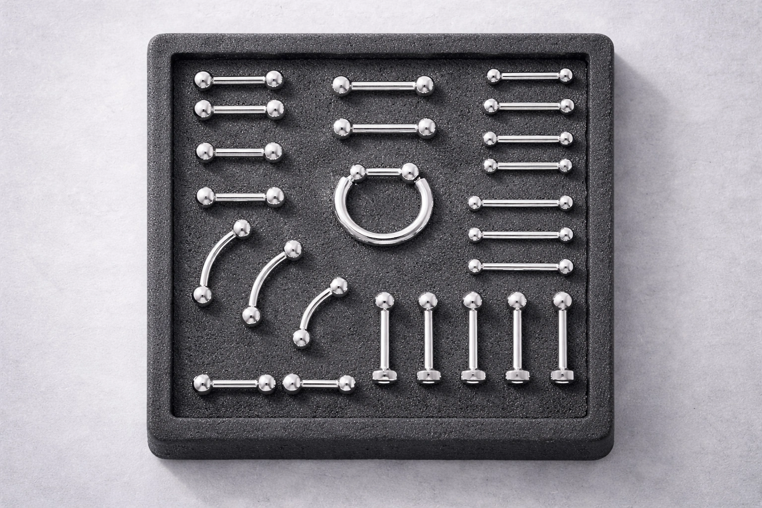 Titanium piercing jewelry product range displayed in organized foam tray
